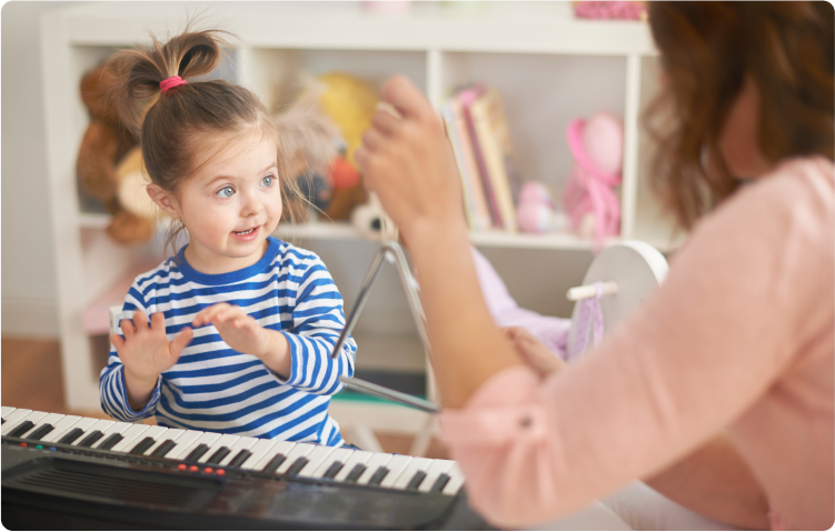 Young girl playing the piano as her mother plays the triangle